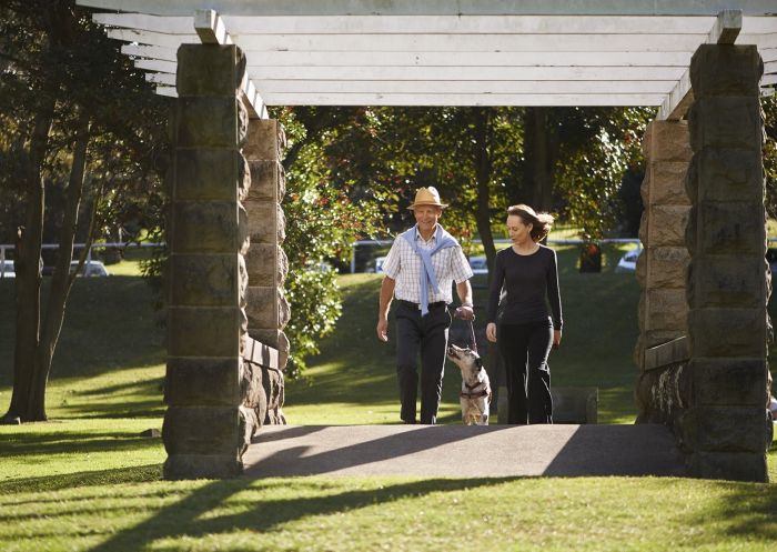 Couple with a dog walking through Centennial Parklands, Moore Park