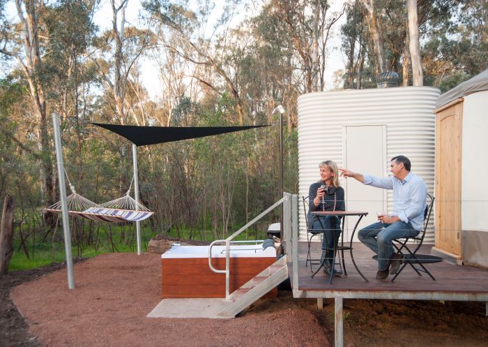 Couple sitting on the deck and enjoying drinks and nature at Yurt in Talo Retreat, Moama
