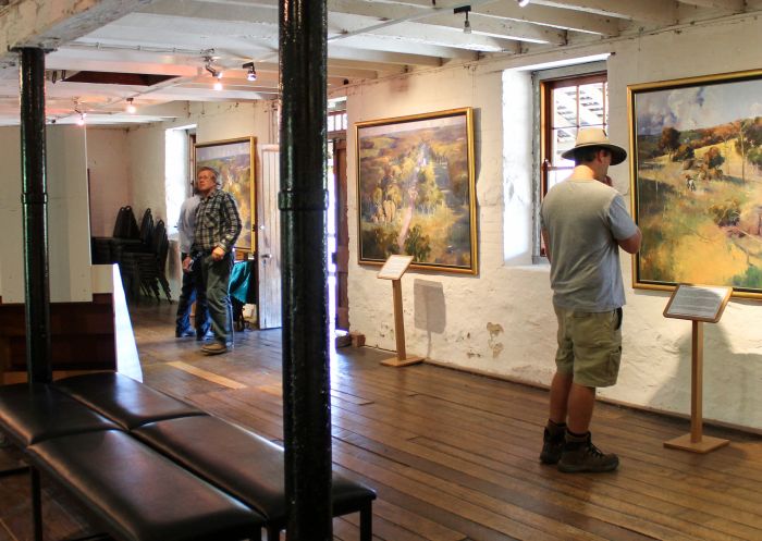 Man viewing paintings on display at McCrossin's Mill Museum, Uralla