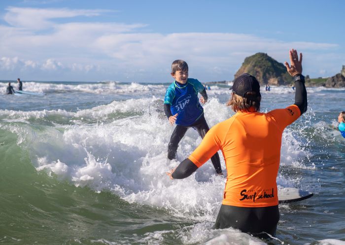 Young boy learns how to surf at Port Macquarie Surf School at Flynn's Beach, Port Macquarie