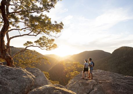Couple watching a scenic sunset over the Hawkesbury Valley from the Vale of Avoca lookout in Grose Vale