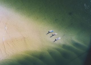 Aerial overlooking stand up paddleboarders on Wallis Lake
