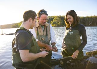 Ein Paar genießt eine Tour mit Captain Sponge's Magical Oyster Tours auf dem Pambula River, Pambula.