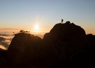 Hiker enjoying a scenic sun set from the top of a mountain at Kosciuszko National Park, Kosciuszko - Credit: Tourism Snowy Mountains