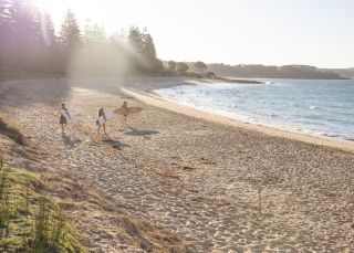 A group of friends preparing for a surf at Murramarang Beachfront Holiday Resort in South Durras