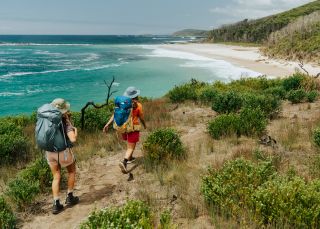 Friends hiking on a coastal track towards a beach, Pretty Beach - Credit: NPWS
