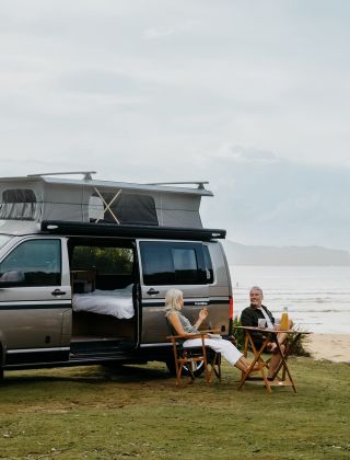 A couple sitting in front of a campervan, NRMA Ocean Beach Holiday Resort, Umina Beach 