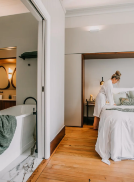 Woman in hotel room with large bath and bed at Littlebourne Guest House