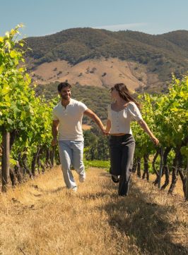 Couple running through the vineyard at Logan Wines, Apple Tree Flat