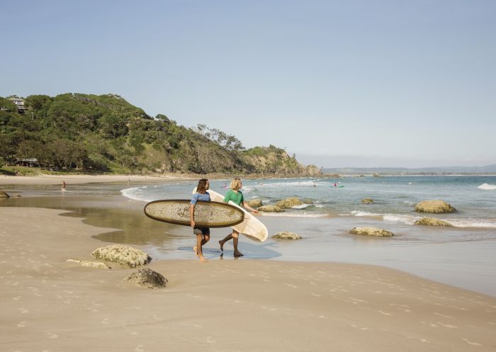 Two surfers holding their longboards survey Wategos Beach, Byron Bay