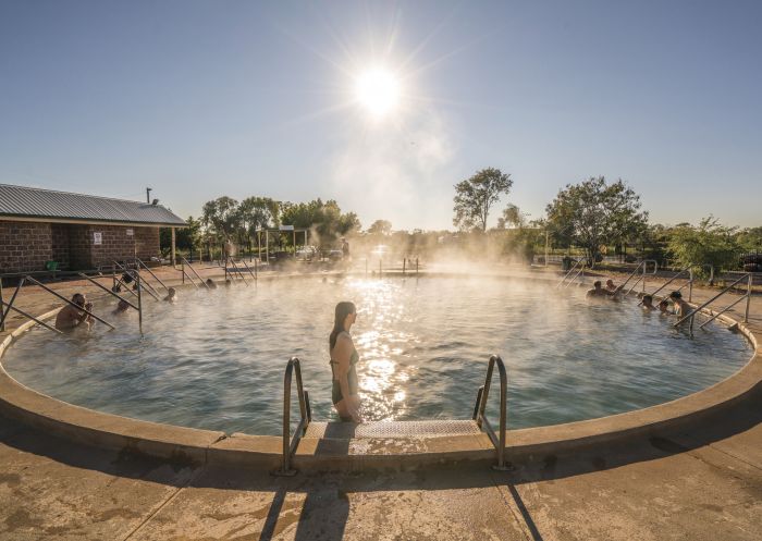 Eine Frau steigt in das dampfende Wasser der Lightning Ridge Bore Baths, Lightning Ridge.