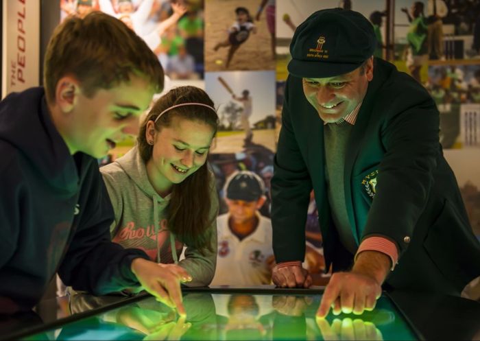 A guide showing two kids cricket memorabilia, Bradman Museum, Bowral