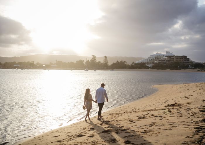 Couple enjoying a walk along Ettalong Beach at sunset