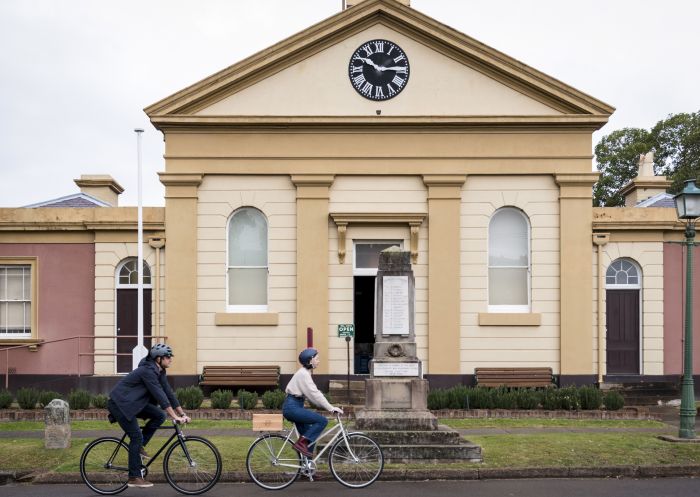 Couple riding past the Morpeth Museum in Morpeth, Hunter Valley 