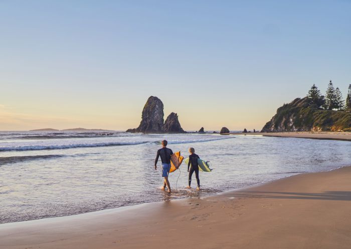 Vater und Sohn gehen morgens zum Surfen zu den Glasshouse Rocks in Narooma.