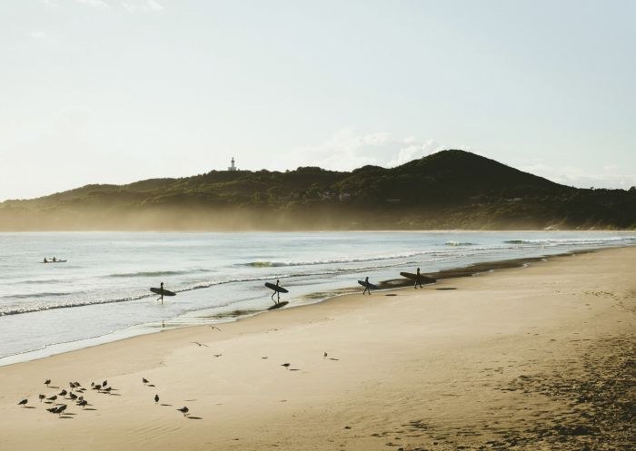 Surfers catching morning waves at Belongil Beach in Byron Bay, North Coast