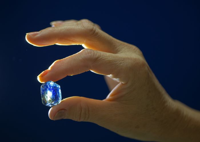 Fossicker in Inverell holding a raw sapphire up to the light, Glen Innes and Inverell Area
