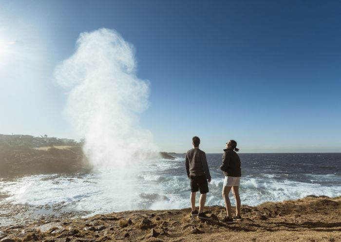 一對夫婦正在觀看凱阿瑪噴水洞（Kiama Blowhole）噴出的水柱