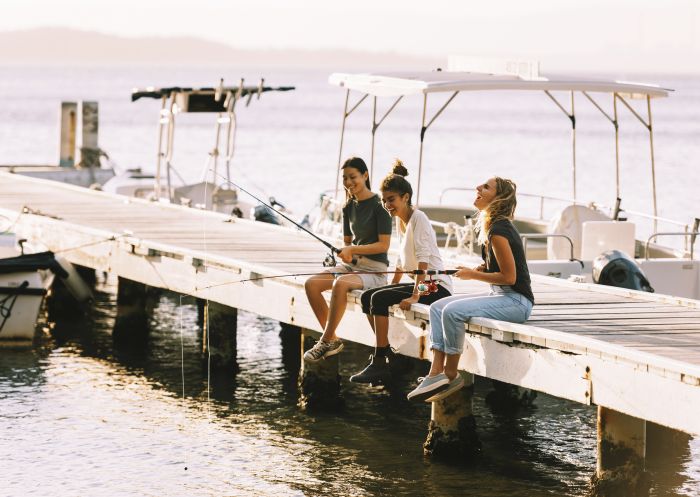 Friends fishing off the jetty at Raffertys Resort in Lake Macquarie, North Coast