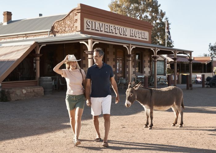 Couple with a local donkey outside the Silverton Hotel at Silverton in Broken Hill, Outback