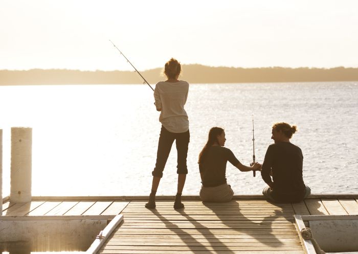 Friends fishing off the jetty at Raffertys Resort in Lake Macquarie, North Coast