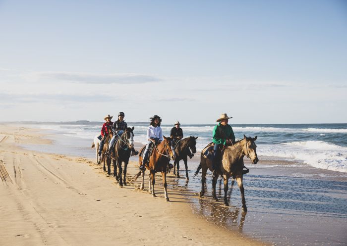 Small group enjoying a beach horse riding experience with Horse About Tours on Nine Mile Beach, Tuncurry
