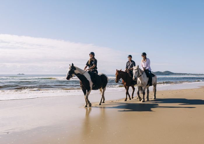 Group enjoying a horse-riding experience along Tyagarah Beach with Zephryr Horses in Byron Bay.