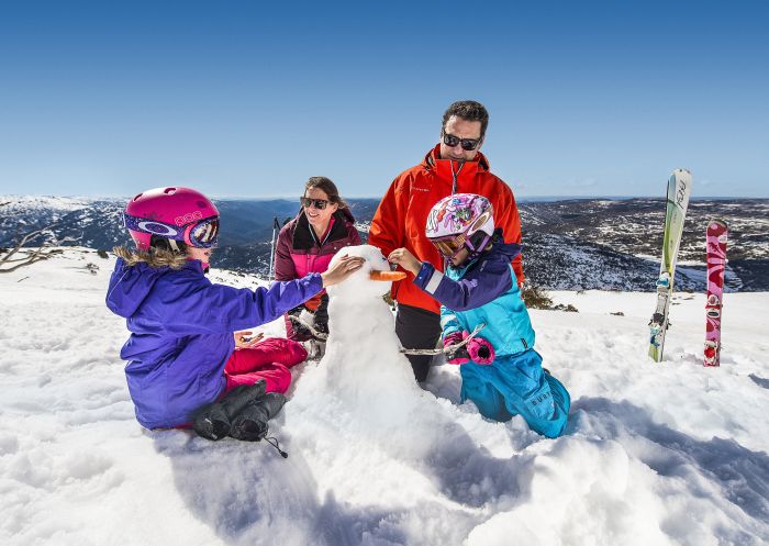Family building a snowman at Perisher Ski Village in the Snowy Mountains after a day of skiing