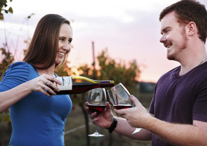 Couple enjoying a bottle of red at sunset at Petersons Armidale Winery and Guesthouse in Armidale