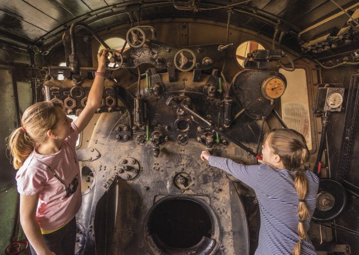 Young girls exploring the historic locomotives on display at the Sulphide Street Railway and Historical Museum in Broken Hill, Outback NSW