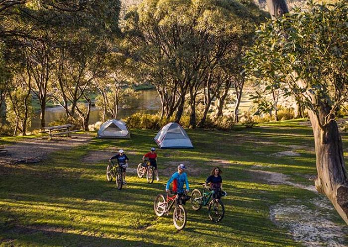 A family unloads bikes from a van and walks towards tents at Thredbo Diggings campground, Kosciuszko National Park