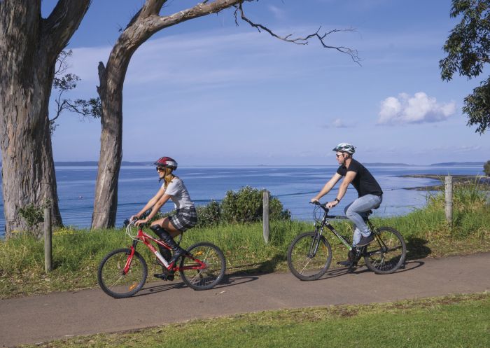 Couple cycling and enjoying the scenic coastal views along Jervis Bay, South Coast