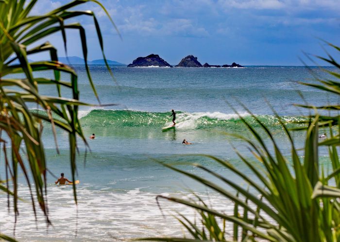 Surfers catching waves off Wategos Beach in Byron Bay with views across to Julian Rocks, Byron Bay