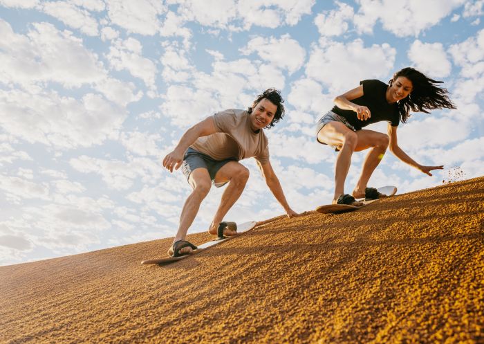 Couple sandboarding down a sand dune, Perry Sandhills