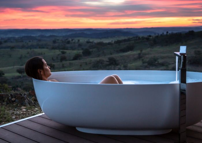 Woman enjoying a relaxing bath with scenic views across the Mudgee countryside at Sierra Escape, Mudgee