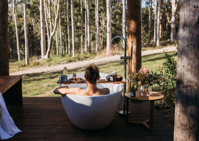 Woman enjoying an outdoor bath on a deck at Carawirry Forest Escape, Dungog - Credit:&nbsp;Jess Porter Photography