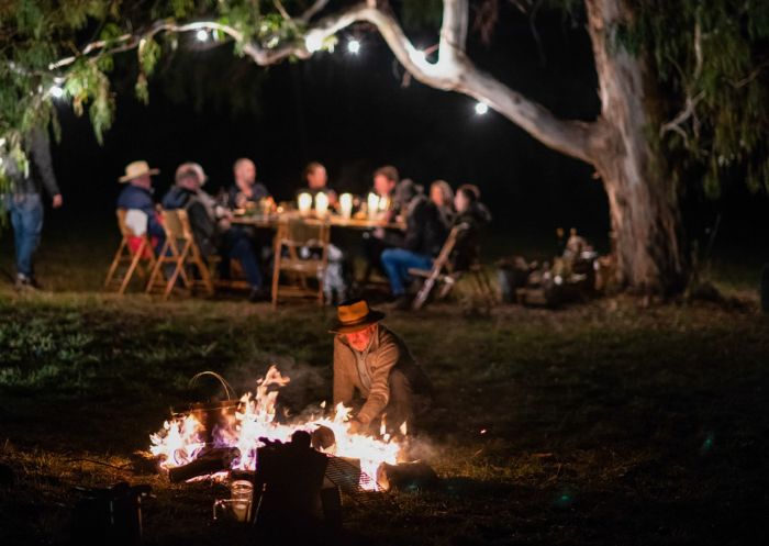 Group enjoying dinner near camp side fire, Orange Winter Fire Festival 
