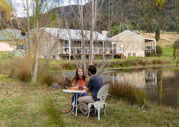 Couple enjoying food and wine outdoors at Starline Alpaca Farmstay, Hunter Valley