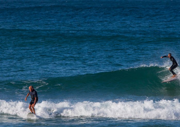 Surfers catching a wave off Town Beach, Port Macquarie