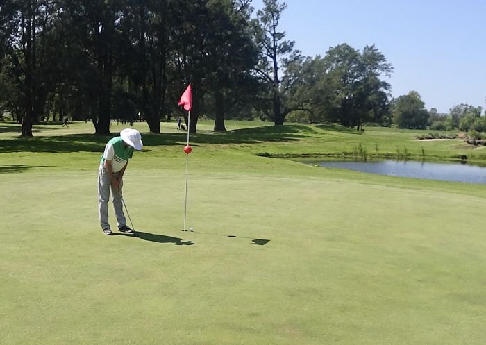 一名男子在綠地上打高爾夫球，背景是樹木和湖泊。圖片來源：詹伯魯高爾夫俱樂部 ( 占布魯（Jamberoo） 高爾夫球 Club) 的戴夫·蘭森 (Dave Ransom)。 