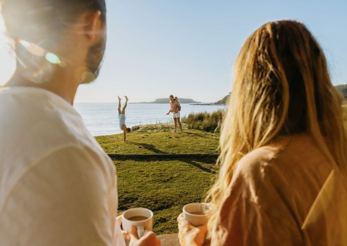 Children playing beside a beach with their parents looking on, NRMA Murramarang Beachfront Holiday Resort, South Durras