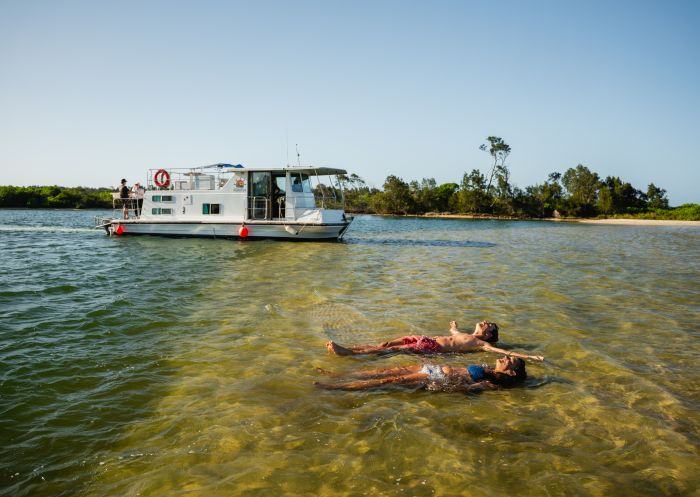 Boat with guest swimming in lake, Forster Houseboat Hire, Forster