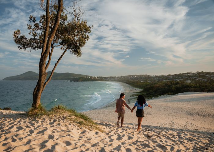Couple walking on dune, One Mile Beach, Forster
