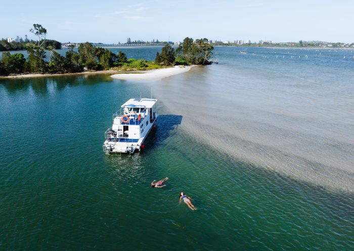 Aerial over of houseboat with two people floating, Forster Houseboat Hire, Forster