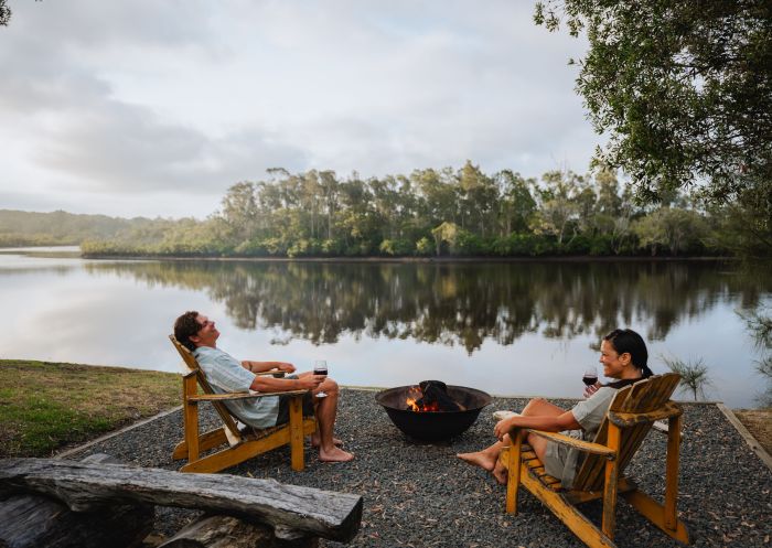 Couple roasting marshmallows by campfireby river, Myall River Camp. Hawks Nest