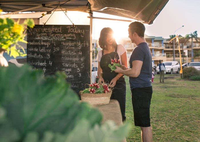 Man shopping at market stall with sunrise, Kiama Farmers' Markets, Kiama