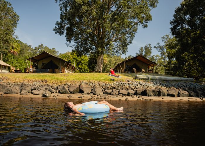 Man floating on river with donut float, Myall River Camp, Hawks Nest