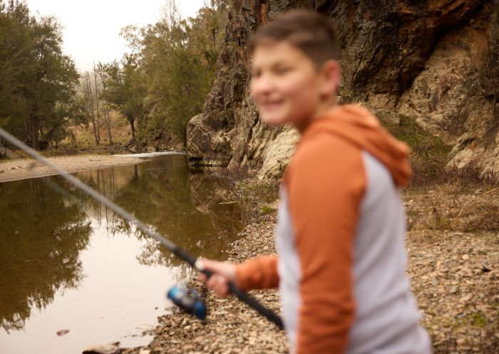 Boy fishing along the river at Sofala Campsite, Sofala