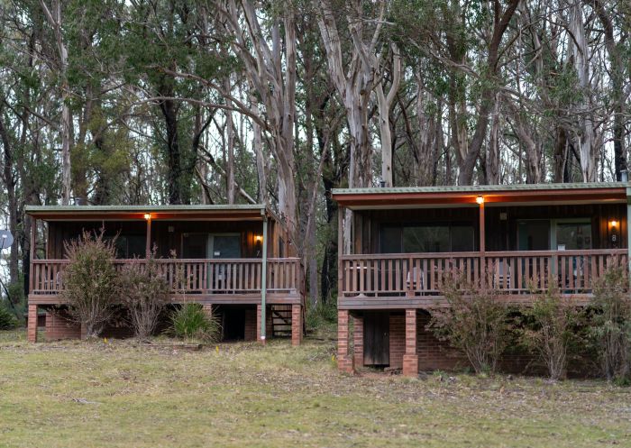 A pair of cabins on a grassy area in front of trees, Jenolan - Credit: Jenolan Caves | DCCEEW