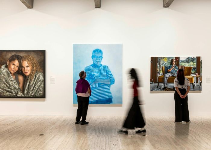 Visitors walking past artworks at Archibald, Wynne and Sulman Prizes 2025 Exhibition, Sydney